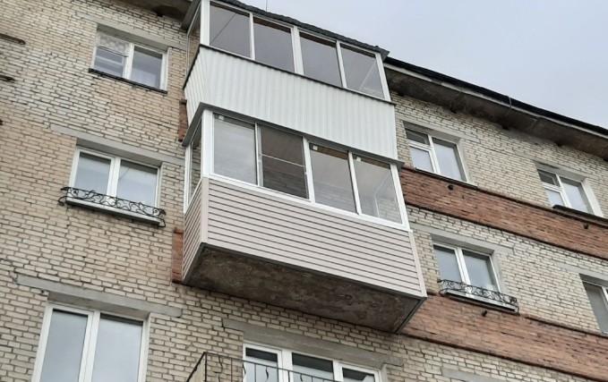 Нестандартный балкон с обшивкой коричневым сайдингом 0